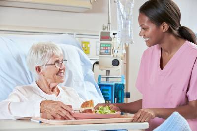 nurse serving to the elder woman her meal